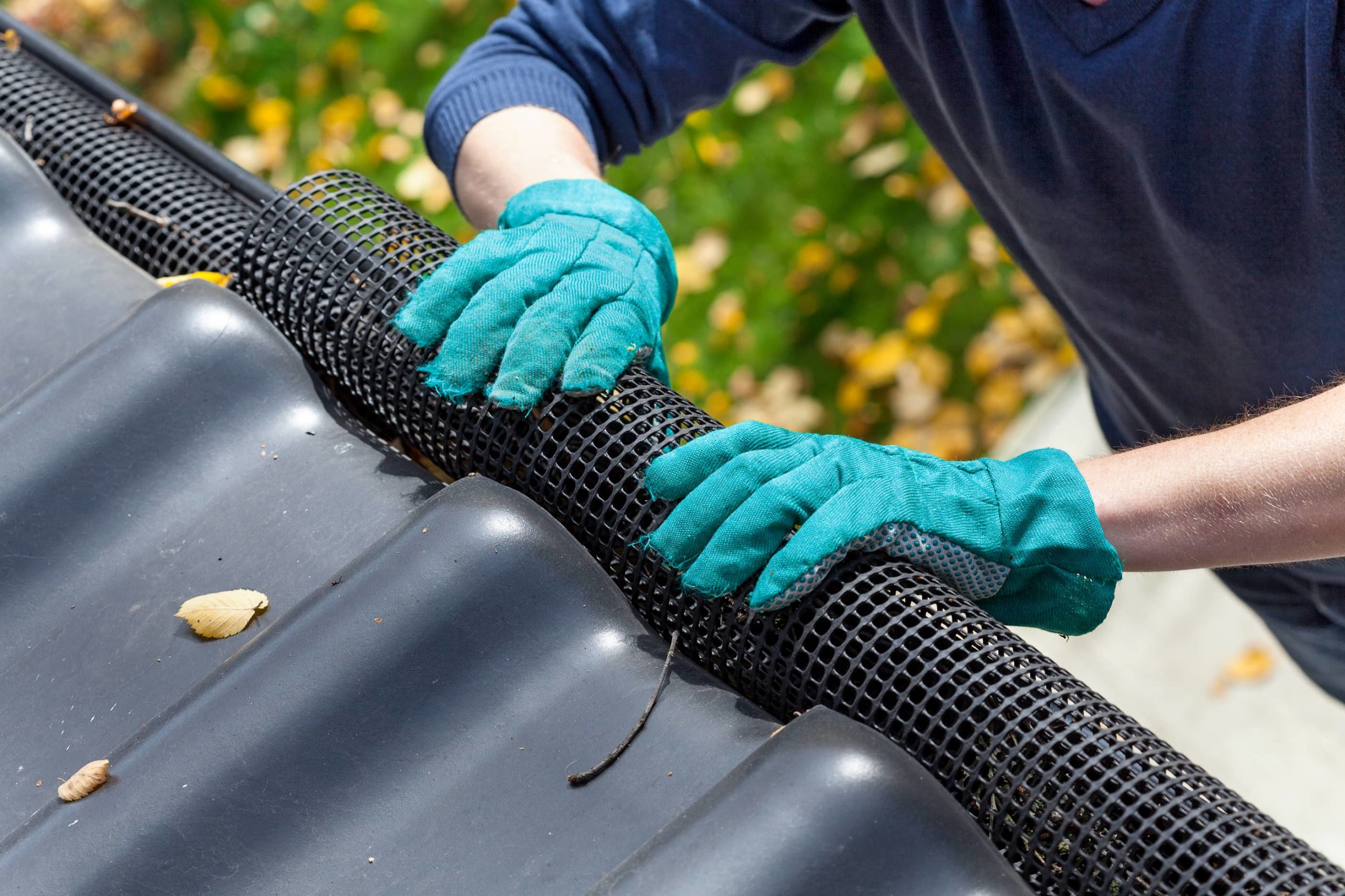 This is an image of a roofing contractor installing a gutter guard to prevent debris clogging.